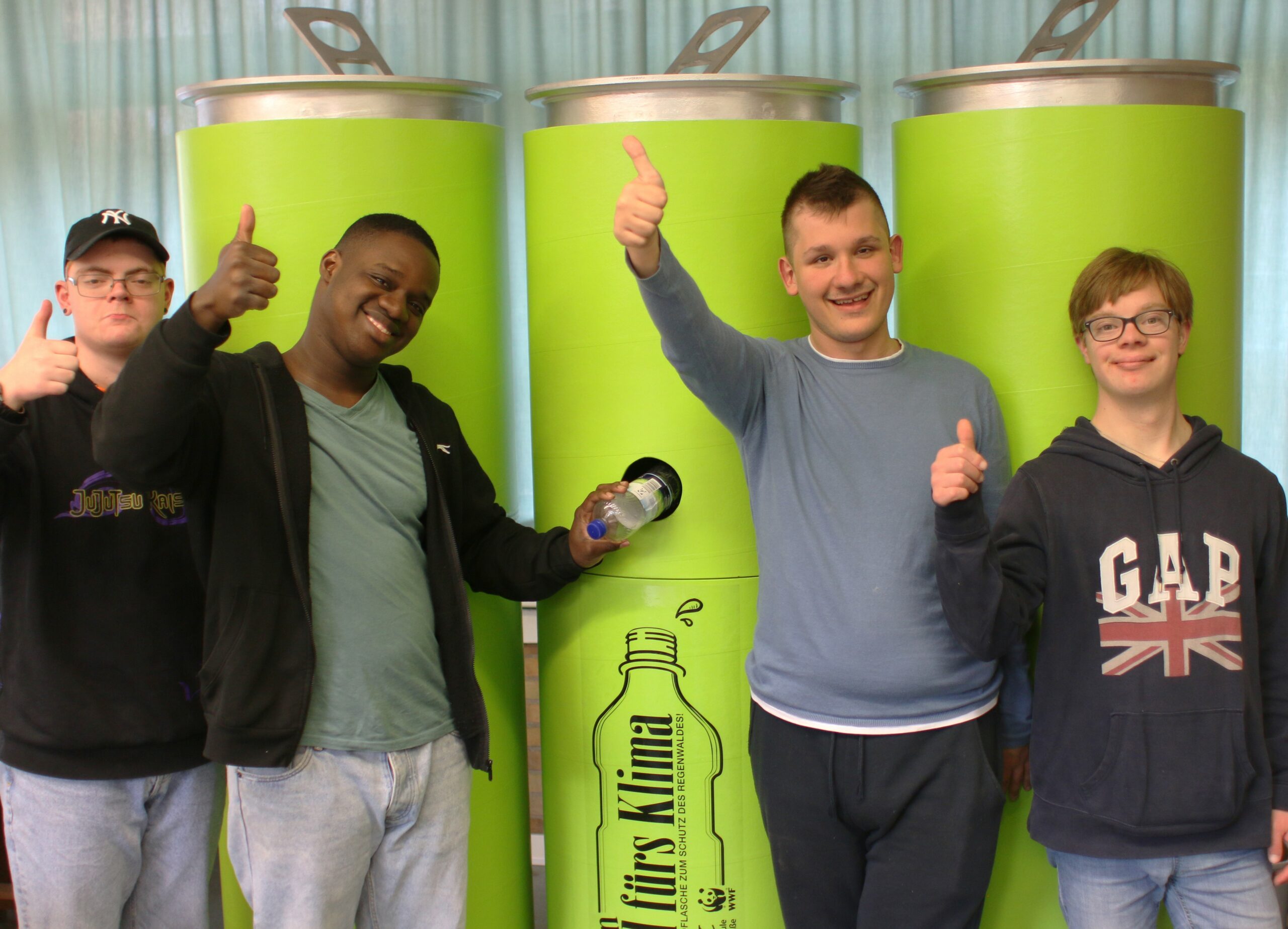 Vier Schüler stehen vor XXL Pfandsammeldosen